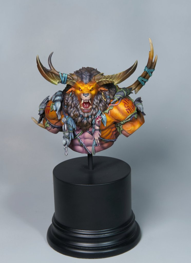 Detailed fantasy creature sculpture with horns, armor, and fierce expression on a black stand.